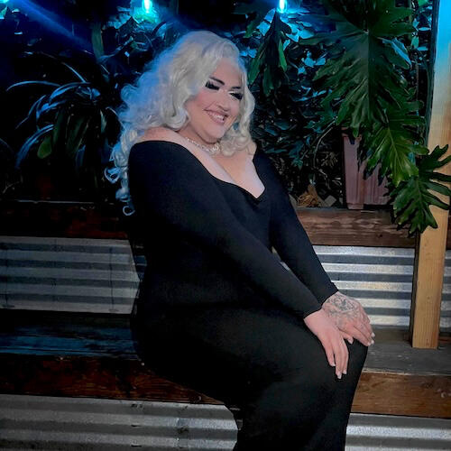 Photo of Carter in a black dress and white-blonde wig