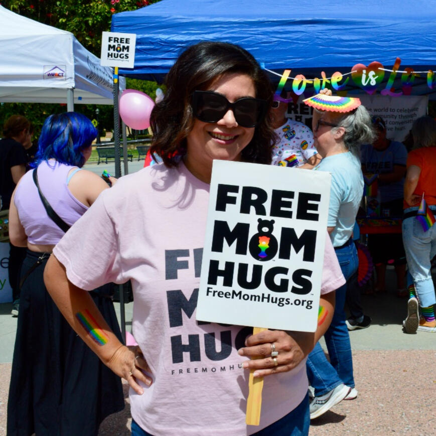 Woman holding a "free mom hugs" sign